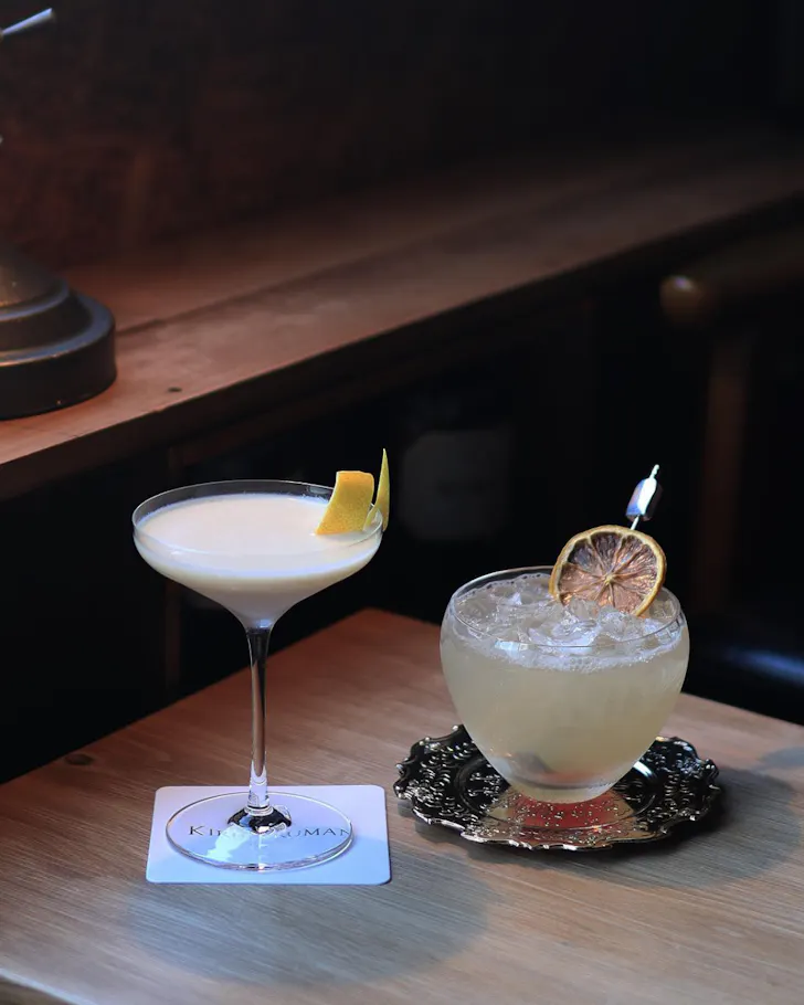 Two aesthetic cocktails on a warm timber table at Kirip Truman, Osaka.
