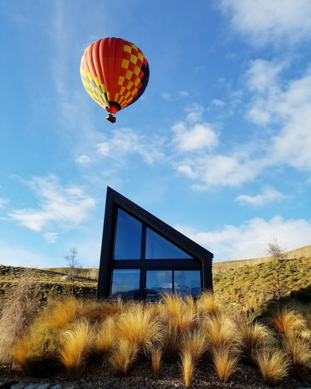 An angular home with a hot air balloon floating above it.
