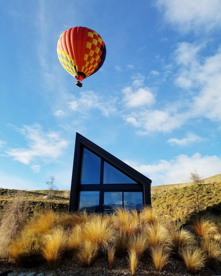 An angular home with a hot air balloon floating above it.