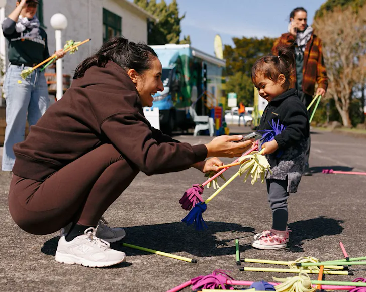 A woman bends down to chat to a small child.