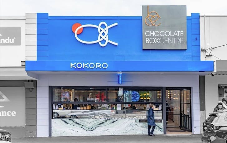 A shopfront with a blue roof and a person walking past. 