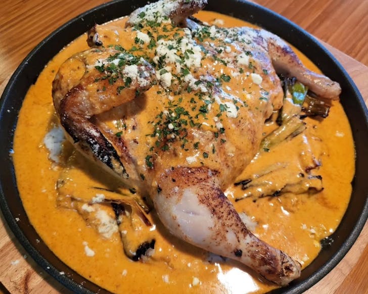 24-hour marinated whole chicken, butterflied, roasted and served whole on a plate of crispy sticky rice with sauce.