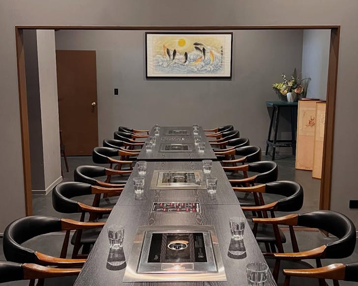 A long row of tables and chairs with gas cookers embedded into the tables for Korean BBQ.