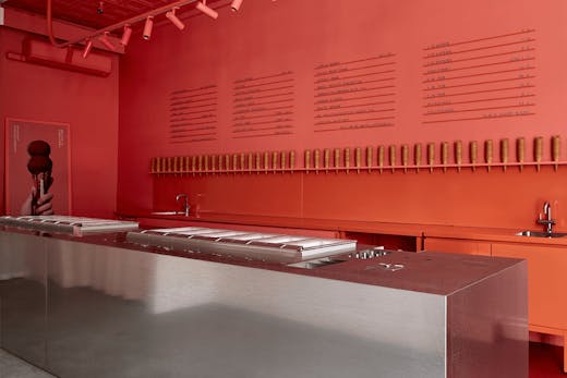 A large red wall with a metal island bench.