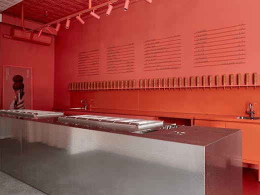 A large red wall with a metal island bench.