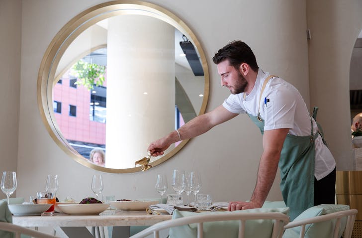 man pouring sauce on steak