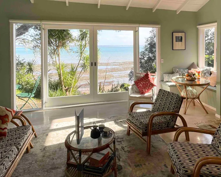 A view out to the beach from Kōtare Cottage one of the best romantic Auckland stays