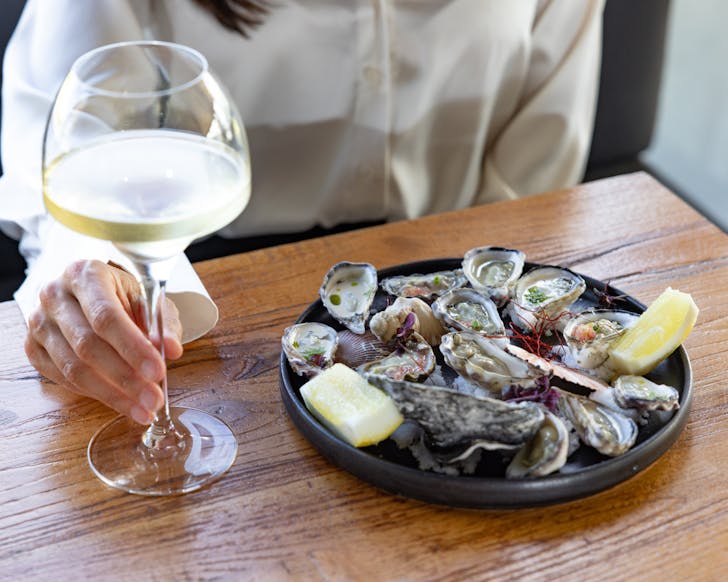Hand on wine glass and plate of oysters