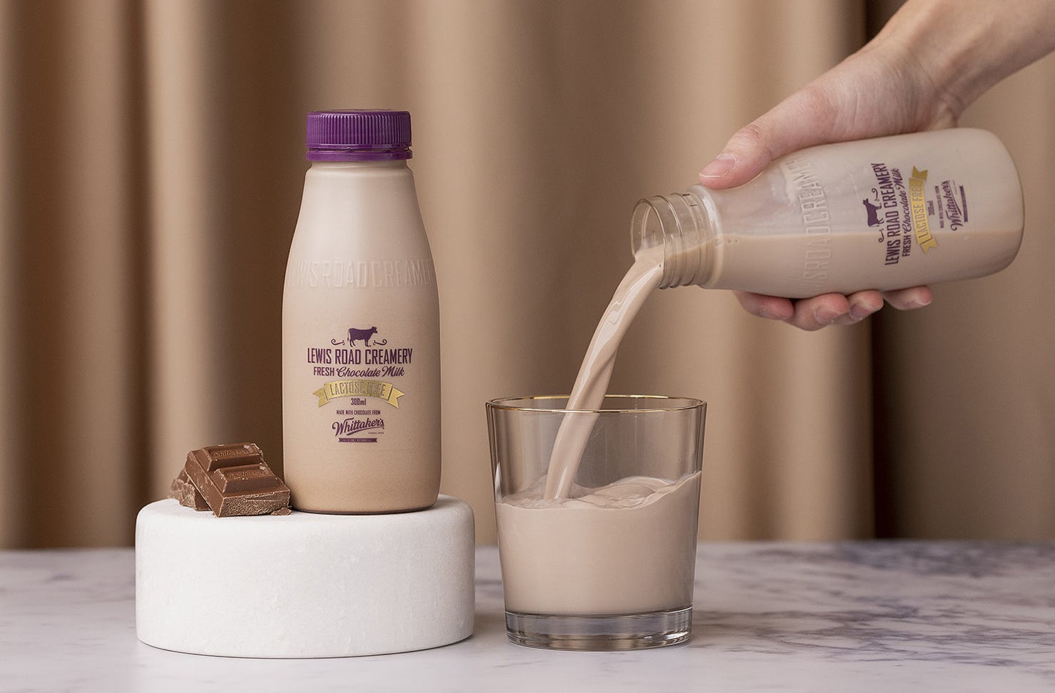 A person pours a glass of Lewis Road Lactose Free Chocolate milk.