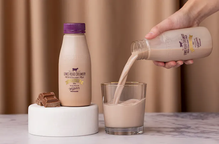 A person pours a glass of Lewis Road Lactose Free Chocolate milk.