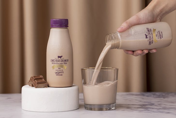 A person pours a glass of Lewis Road Lactose Free Chocolate milk.