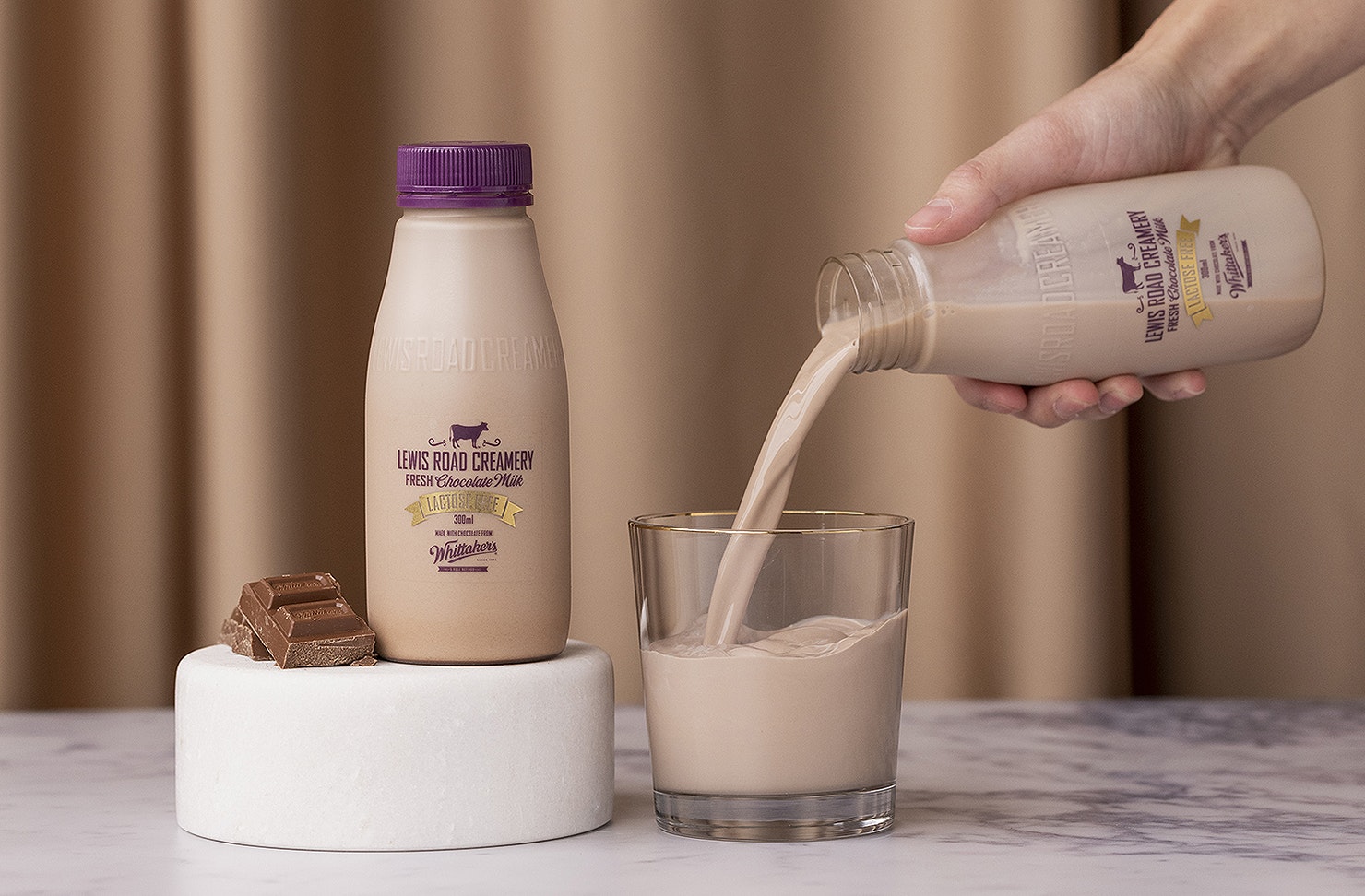 A person pours a glass of Lewis Road Lactose Free Chocolate milk.
