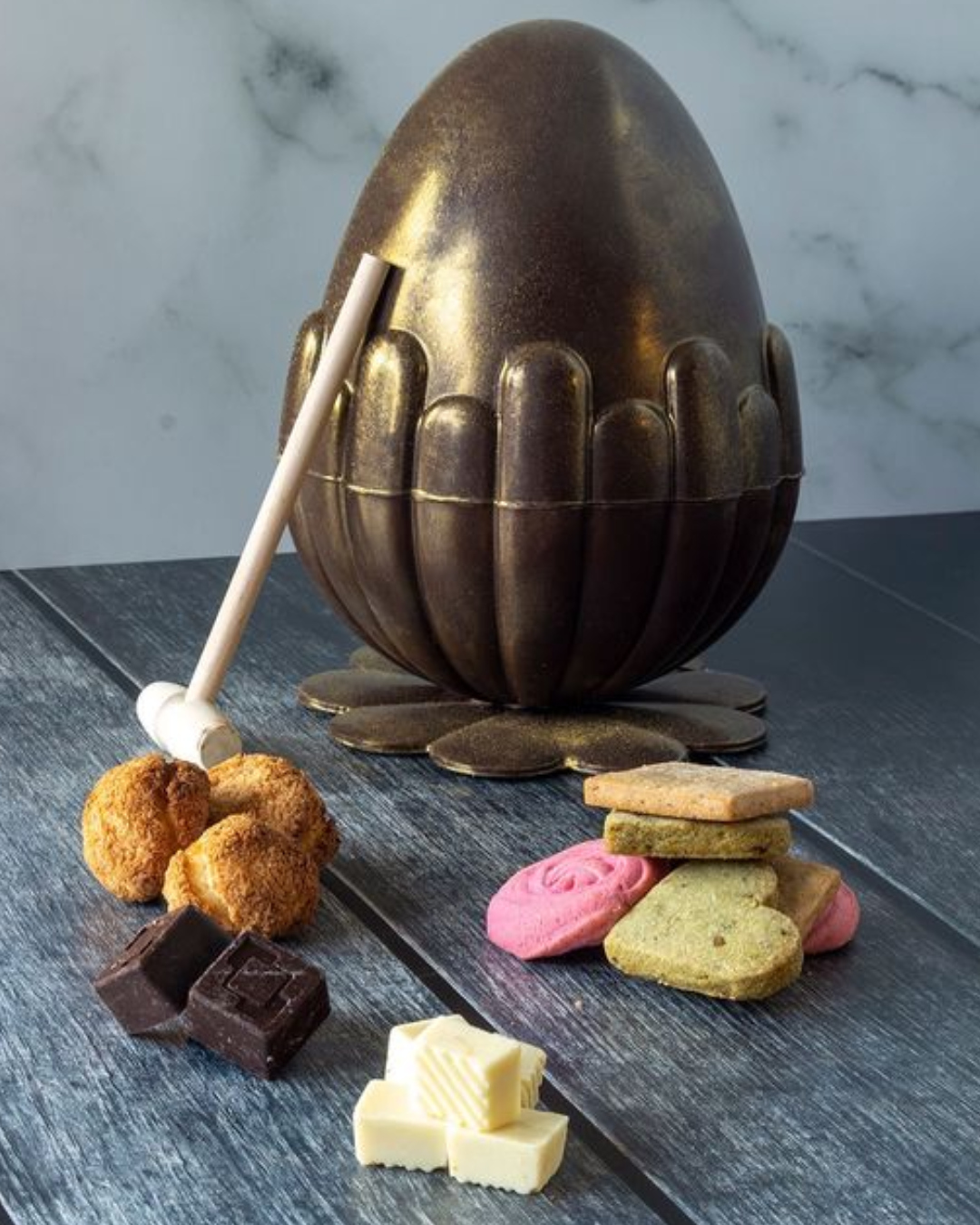 A chocolate egg with a small wooden hammer next to it.
