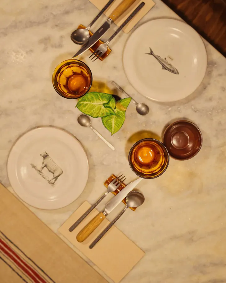 An overhead shot of a set table at La Sosenga, featuring vintage plates and cutlery.