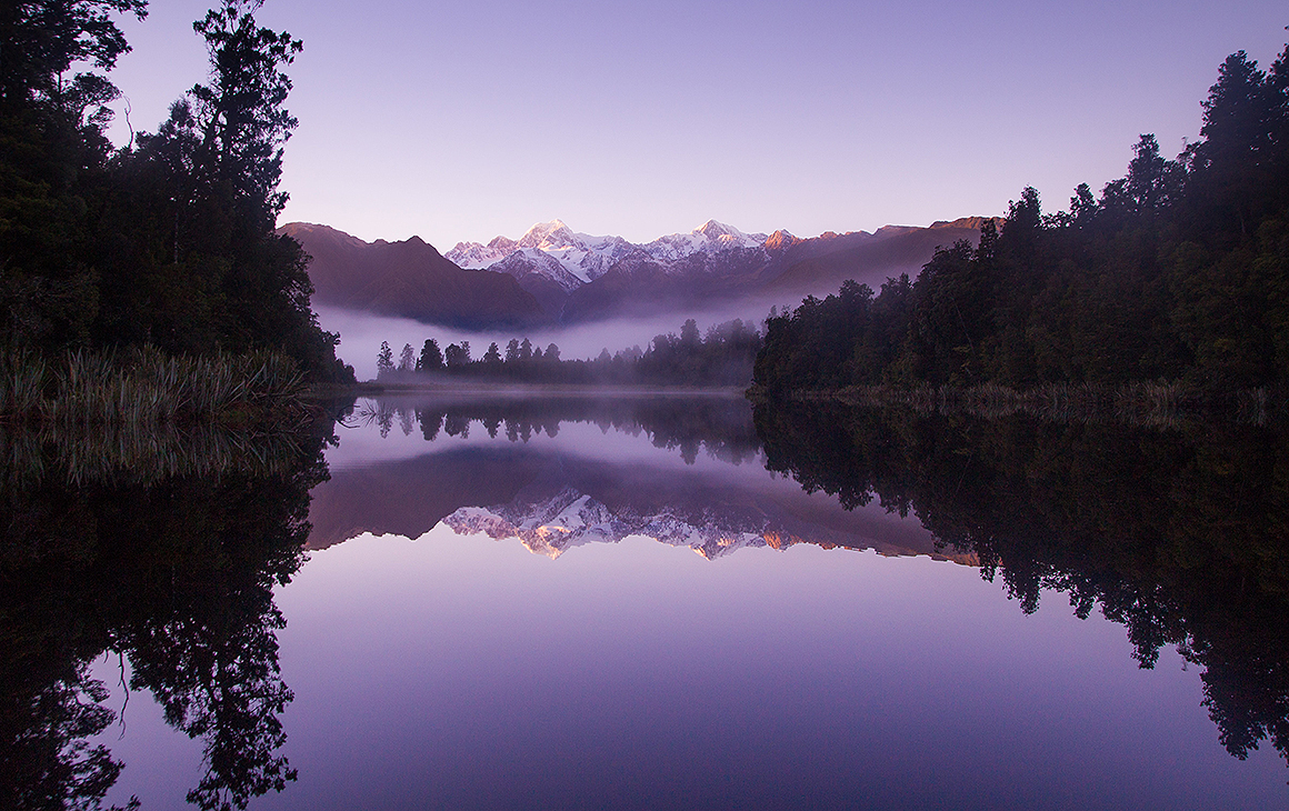 Lake Matheson with a purple hue seen at dusk.