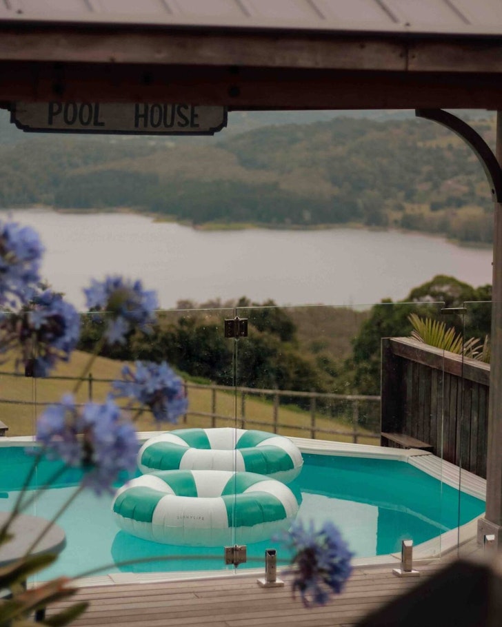 A view of the pool with a lake behind at The Lakehouse Folk Cottages Airbnb one of the best accommodation options in Maleny