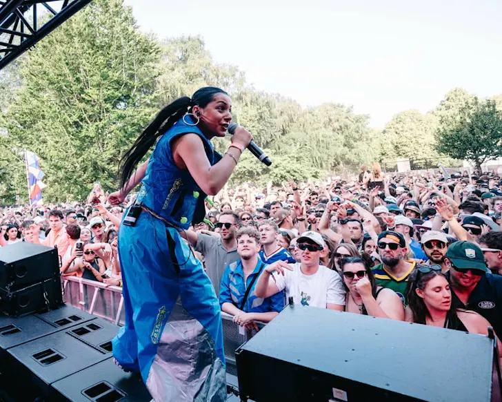 A woman sings to a massive crowd on an outdoor stage.