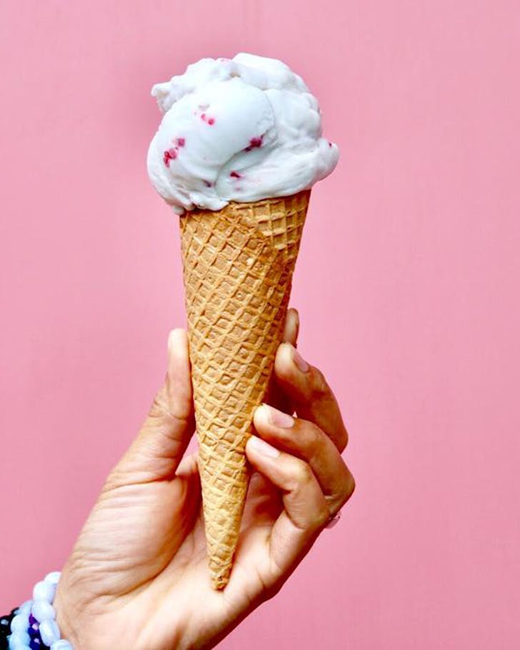 A Lalele Organic ice cream held aloft in front of a pink background.