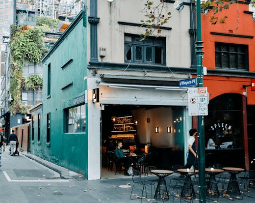 The front of a bar with a laneway with people walking by. 