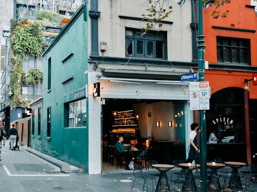 The front of a bar with a laneway with people walking by. 