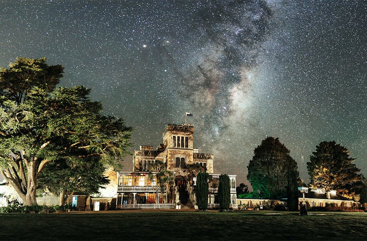 Larnach Castle lit up with the milky way streaking over the top,