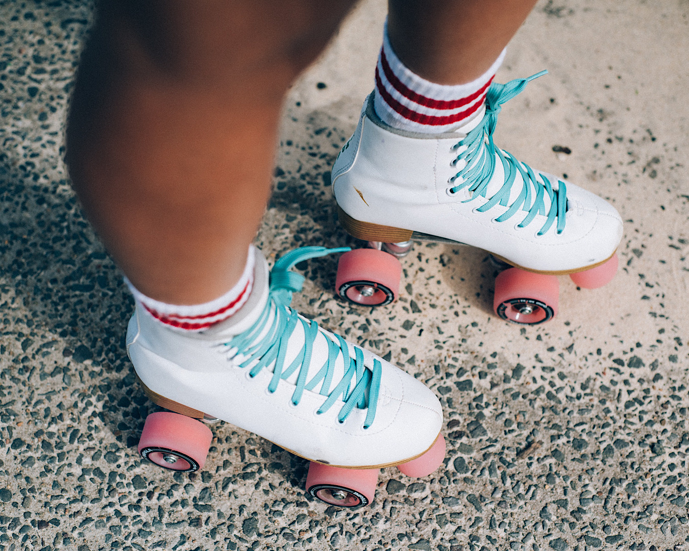 Legs wearing a pair of white roller skates with blue laces, a great thing to do in Auckland. 