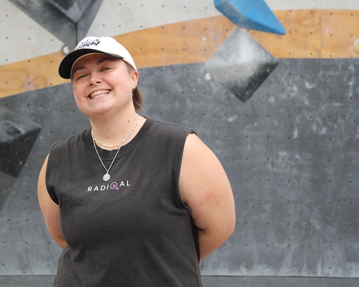 Lauren stands in a bouldering gym looking happy. 