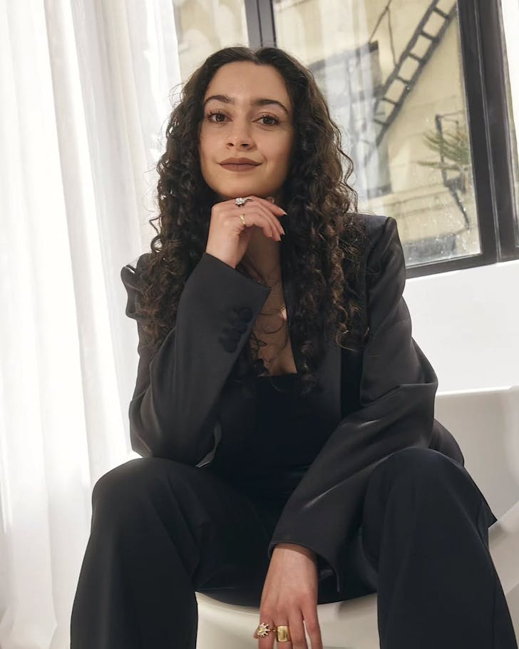 Layla Kaisi sits with her hand under her chin showcasing an LKC diamond ring. 