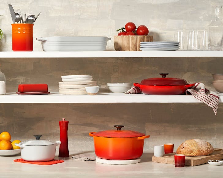 A whole lot of Le Creuset kitchenware on shelves. 