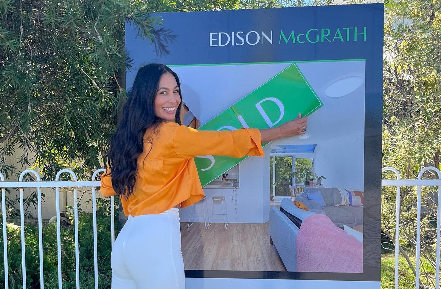 Woman with a sold sticker outside a house