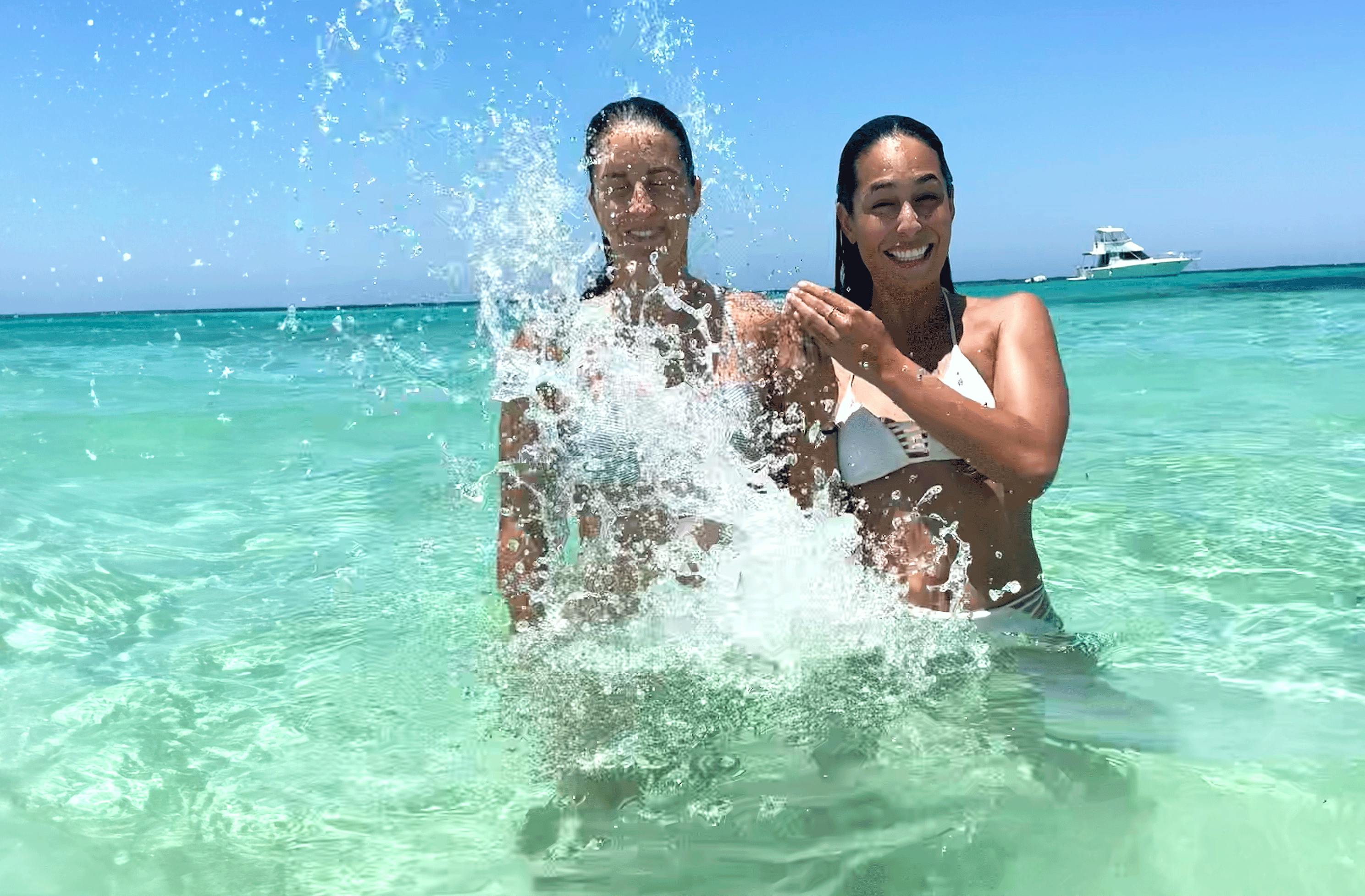 Two woman play in the blue waters of the south pacific