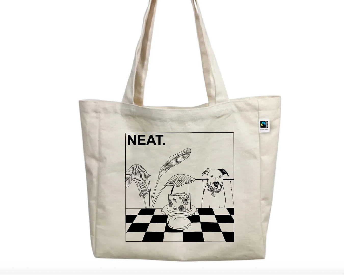 A white tote bag with the word ‘neat’ in capital letters, a line drawing of a dog with a heart nose, a cake on a chequered table, and a large plant. 