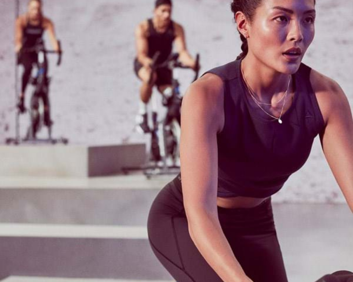 A woman and men on fixed bicycles doing a group workout