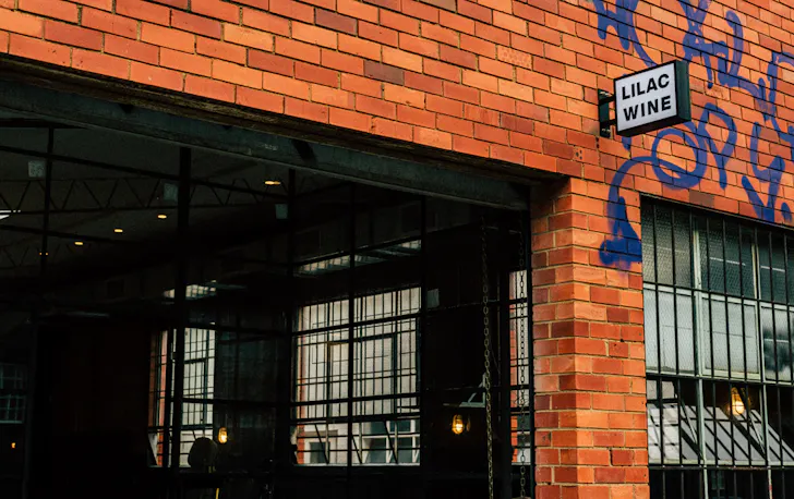 The outside of a brick building with a small black sign.