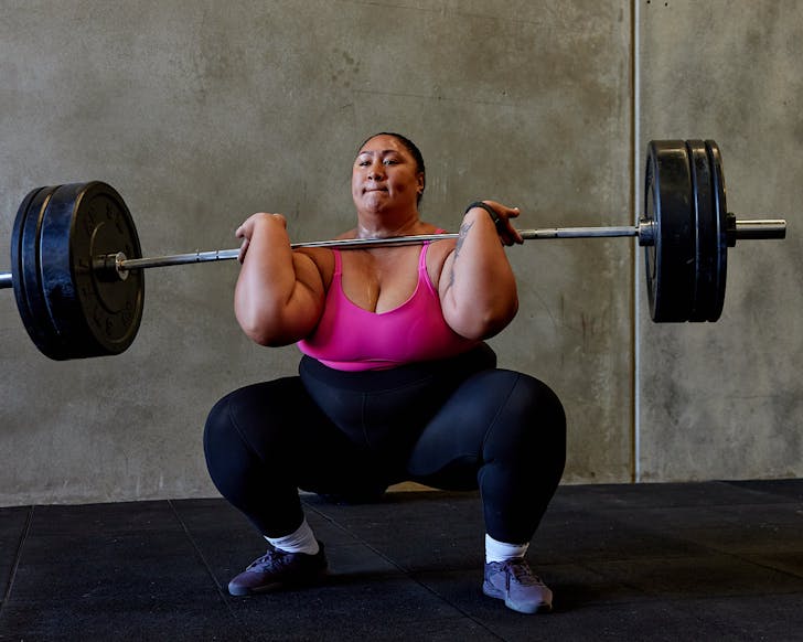 Lilz aka CrossThick powerlifts while wearing a pink sports bra and black leggings by LSKD. 