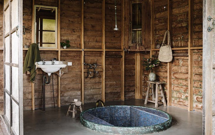 A blue-tiled spa sits in the round of a small timber hut.
