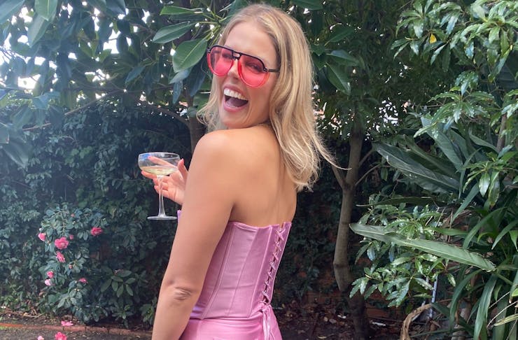 Woman wearing pink corset and pink sunnies holding a cocktail
