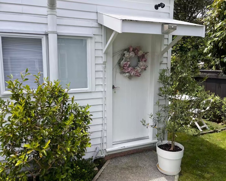 The white weatherboard exterior of Little White Beach Cabin one of the best Wellington Airbnbs