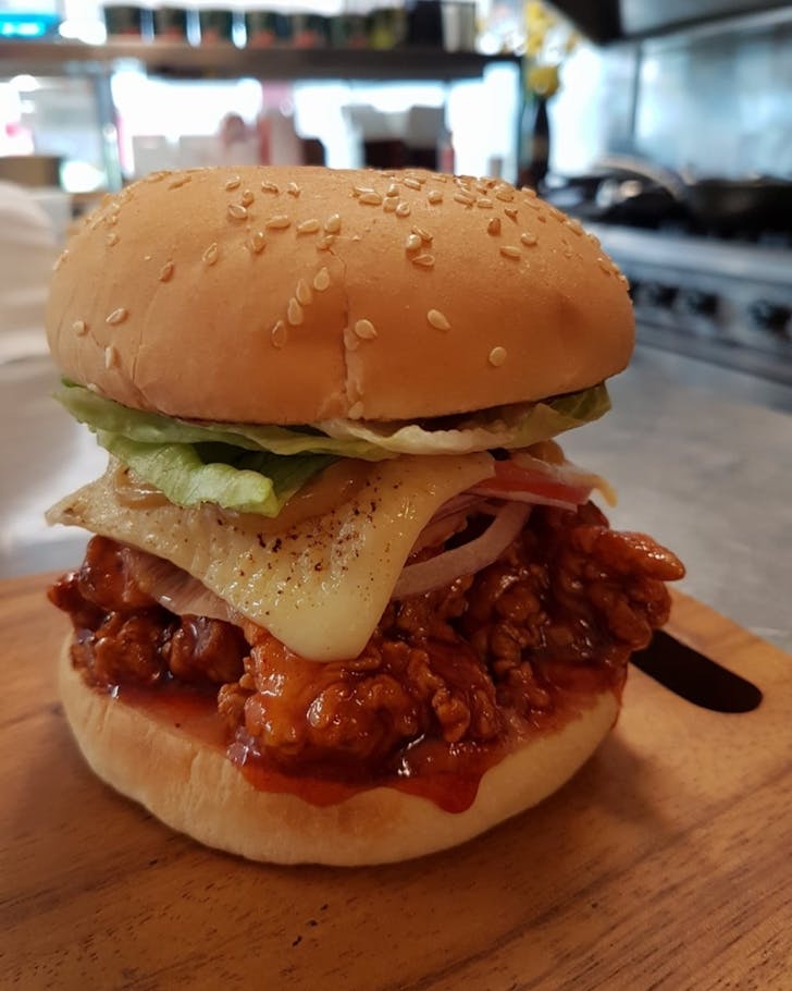 Dakgangjeong burger: spicy crispy chicken, torched Swiss cheese, pickled daikon, housemade cranberry mayo and honey mustard.