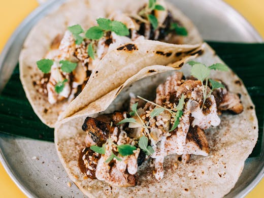 A close up of two jam-packed tacos.