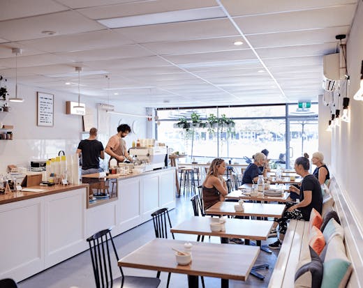 The inside of a white-painted cafe with people dining.