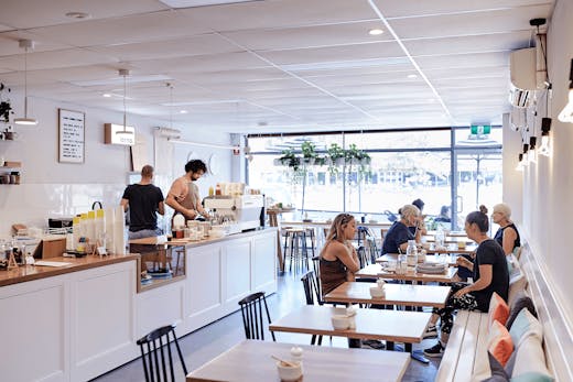 The inside of a white-painted cafe with people dining.