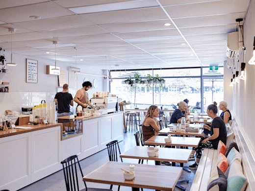 The inside of a white-painted cafe with people dining.