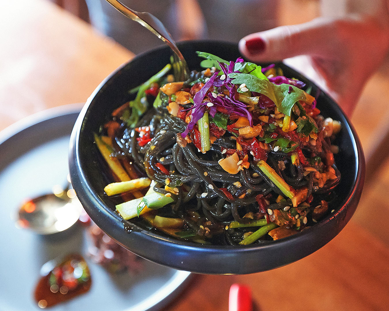 Someone holds up a plate of noodles at Lucky 8.