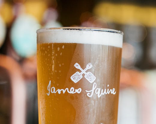 A pint glass of beer with the James Squire logo.