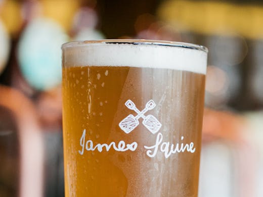 A pint glass of beer with the James Squire logo.
