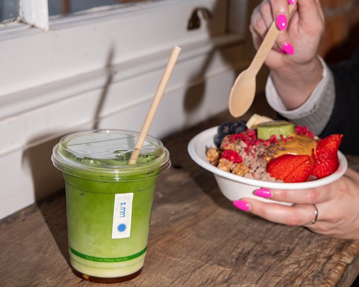 Rachel holds an acai bowl and an iced matcha sits beside her. 