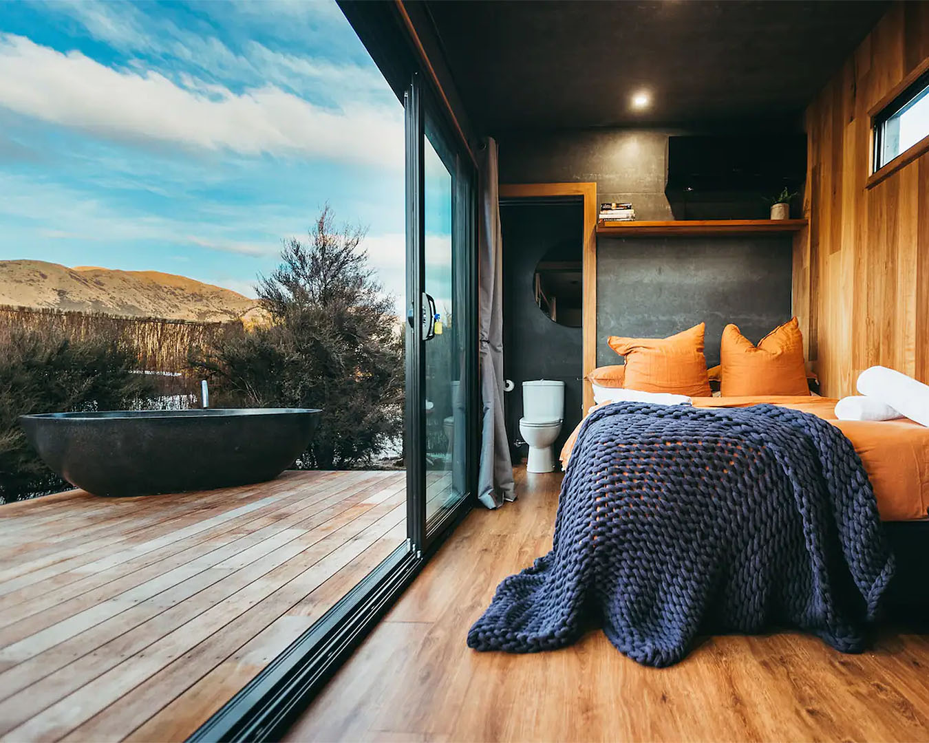 A lovely room looks out onto a bath tub on the deck. One of the best tiny homes in NZ.