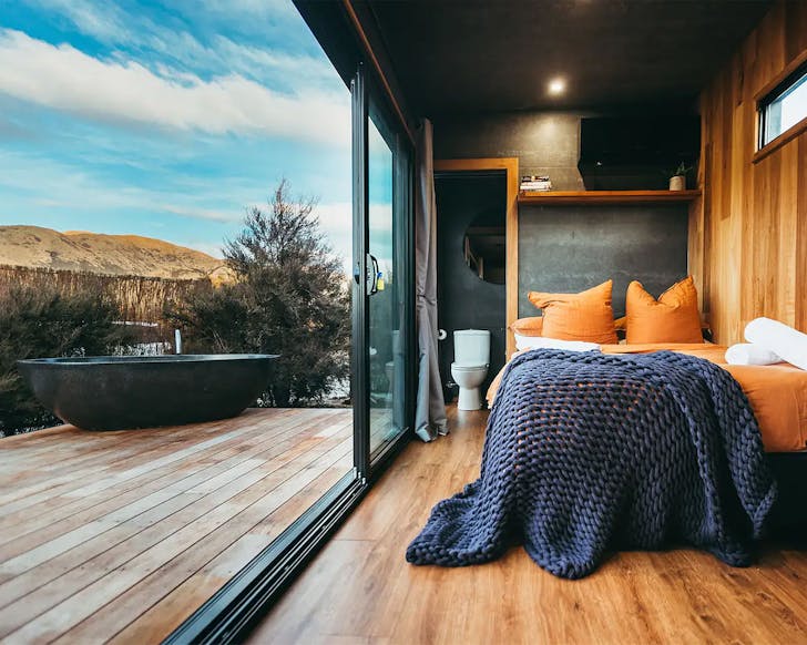 A lovely room looks out onto a bath tub on the deck. One of the best tiny homes in NZ.