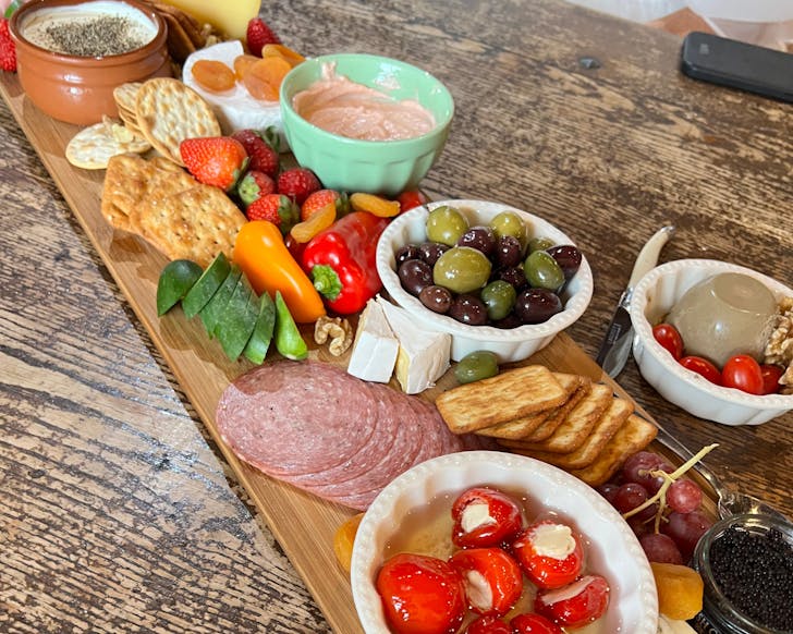 Display of cheeses and vegetables on wooden board